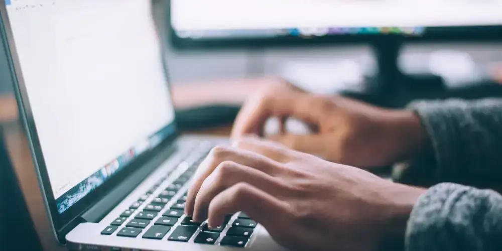 man typing on laptop keyboard
