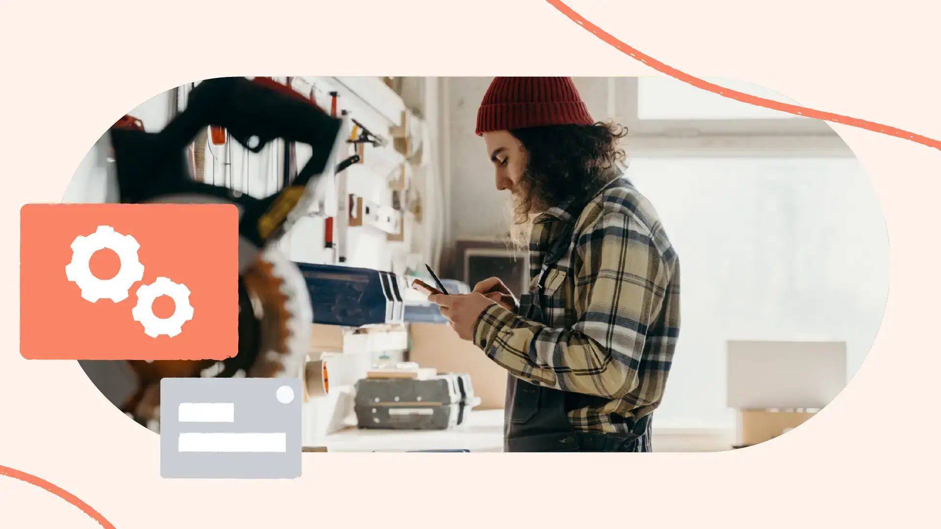 Man with long hair, beanie and overalls in manufacturing shop using his smartphone.